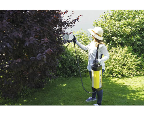 Femeie folosind un pulverizator de grădină pentru combaterea dăunătorilor în grădină.