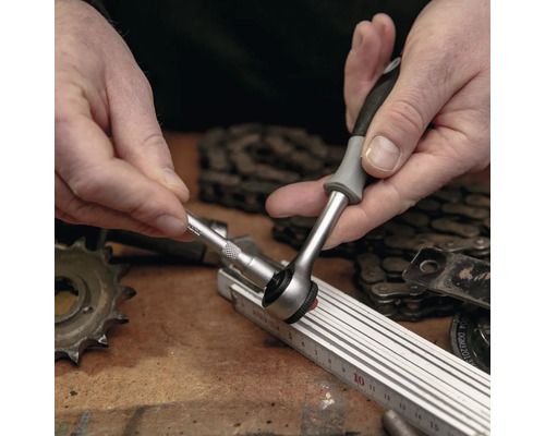 O persoană folosește o cheie tubulară cu clichet pe un banc de lucru.