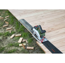 Fierăstrău circular cu acumulator pe podea de lemn cu șină de ghidare și bucăți de lemn