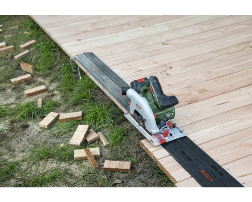 Fierăstrău circular cu acumulator pe podea de lemn cu șină de ghidare și bucăți de lemn