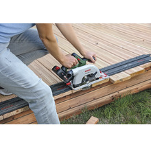 O persoană taie o scândură de lemn cu un fierăstrău circular portabil pe o terasă de lemn.