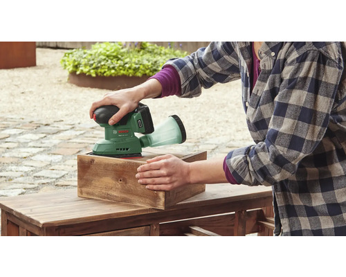 O persoană șlefuiește o bucată de lemn cu o șlefuitoare excentrică fără fir Bosch.