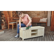 Femeie șlefuind un dulap din lemn cu un șlefuitor excentric în aer liber.