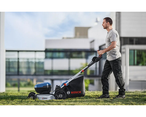 Un bărbat operează o mașină de tuns iarba fără fir Bosch în grădină.