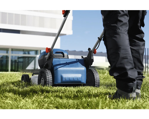 Mașină de tuns iarba în uz pe o suprafață de gazon.