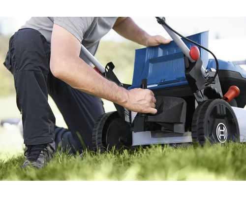 O persoană pregătește o mașină de tuns iarba pentru grădinărit