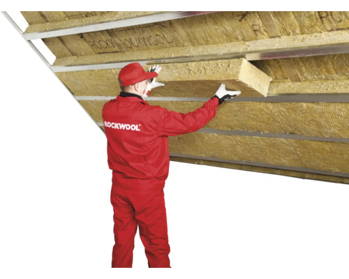 Un muncitor instalează vată izolatoare Rockwool într-un tavan.
