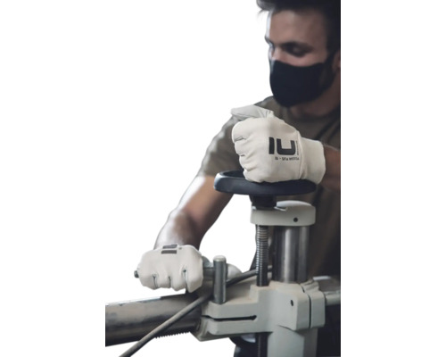 Bărbat cu mască de protecție manevrând un utilaj cu mănuși de lucru