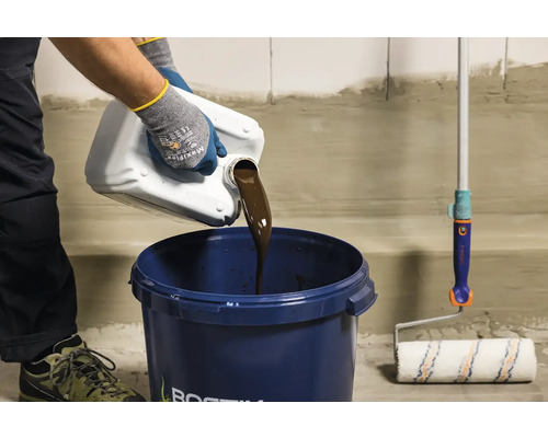 O persoană toarnă lichid dintr-un bidon într-o găleată, lângă o rolă de vopsea.