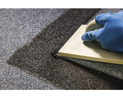 Mână cu mănușă și gletieră pentru rosturi la chituirea plăcilor de podea