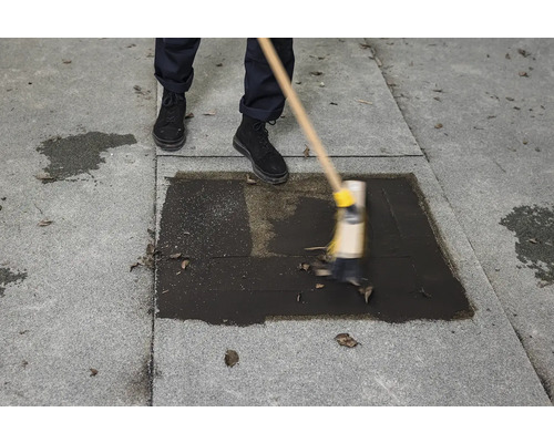 O persoană curăță o suprafață de piatră gri cu o mătură