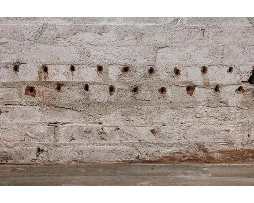 Prim-plan cu un zid de cărămidă cu găuri de foraj.