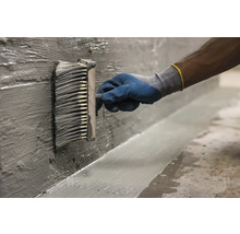 Aplicarea șlamului de etanșare cu o pensulă plată pe un perete.