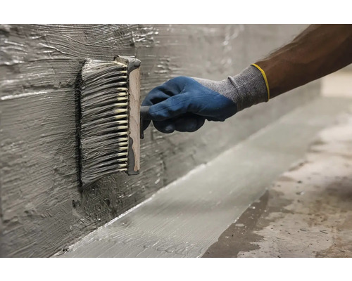 Aplicarea șlamului de etanșare cu o pensulă plată pe un perete.