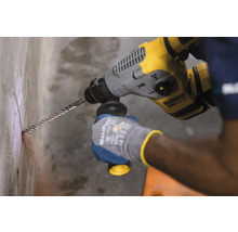 O persoană găurește un perete cu un ciocan rotopercutor.