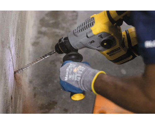 O persoană găurește un perete cu un ciocan rotopercutor.