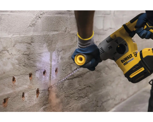 Artizan care găurește un perete cu un ciocan rotopercutor.