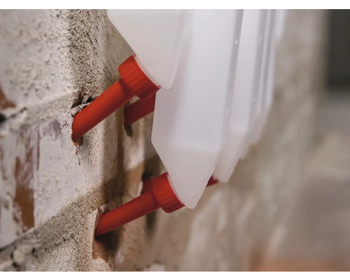 Prim-plan cu hrănitoare din plastic pentru animale atașate pe un perete de cărămidă