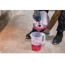 O persoană toarnă lichid dintr-un recipient într-un pahar gradat.