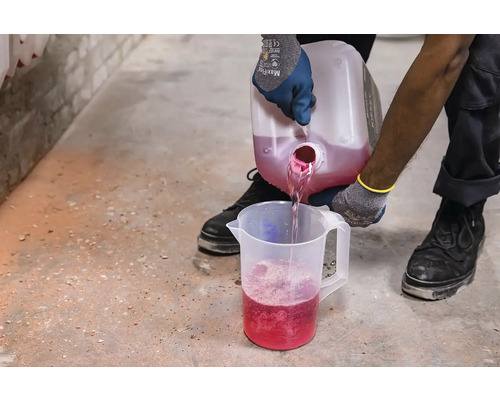 O persoană toarnă lichid dintr-un recipient într-un pahar gradat.