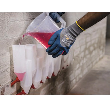 O persoană toarnă lichid într-un adăpător automat pentru animale.