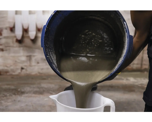 O persoană toarnă mortar dintr-o găleată într-un pahar gradat.