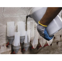 Un muncitor toarnă mortar într-o cutie de mortar pe un zid de cărămidă