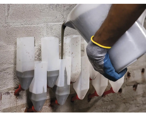 Un muncitor toarnă mortar într-o cutie de mortar pe un zid de cărămidă