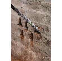 Burghiu care forează o gaură într-un zid de cărămidă