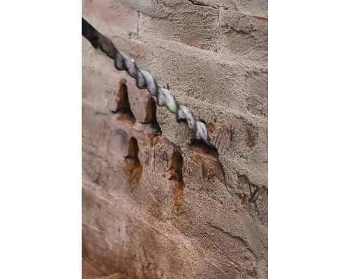 Burghiu care forează o gaură într-un zid de cărămidă