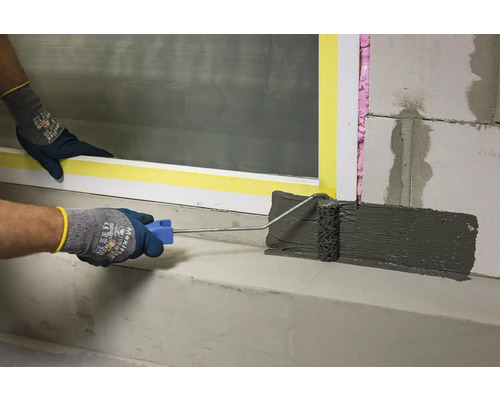 Aplicarea nămolului de etanșare cu o rolă pe beton.