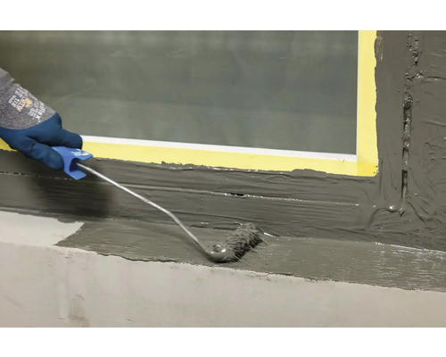 Aplicarea unui material de etanșare cu o rolă de vopsea pe un cadru de fereastră.