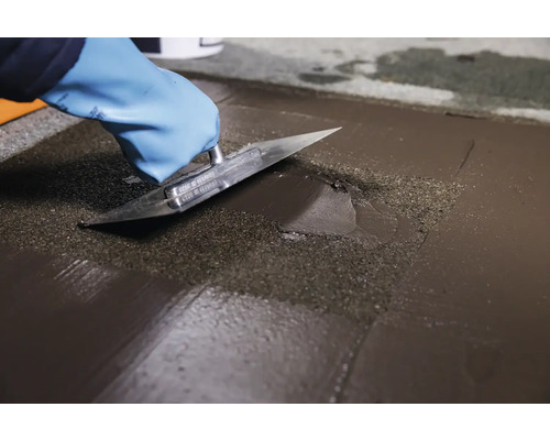 Aplicarea autonivelantei cu o gletieră pe o podea.