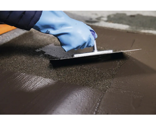 Artizan nivelează șapa autonivelantă cu o gletieră