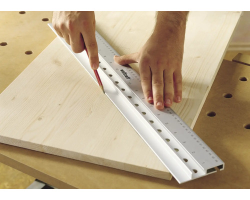 Persoană care trasează o linie cu un creion de-a lungul unei rigle Wolfcraft pe o scândură de lemn