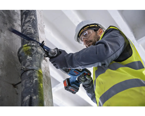 Un bărbat taie o țeavă cu un fierăstrău sabie cu acumulator.