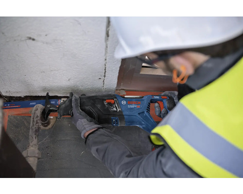 Un bărbat cu cască de protecție taie o țeavă cu un fierăstrău sabie Bosch.