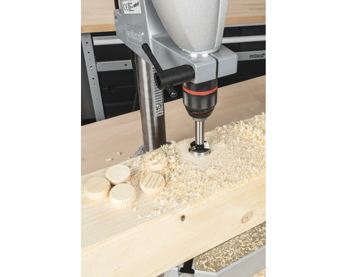 Mașină de găurit care găurește dibluri de lemn într-o scândură de lemn