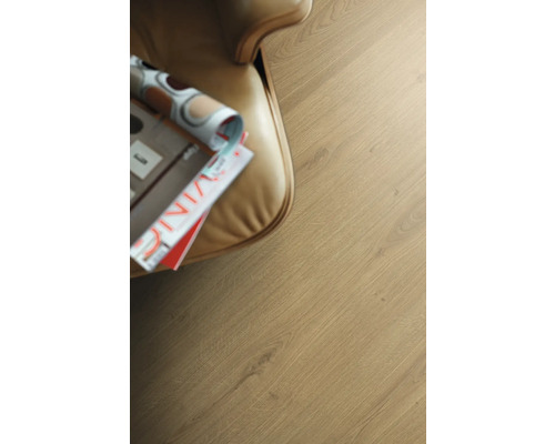 Prim-plan cu o podea laminată cu revistă lângă un fotoliu