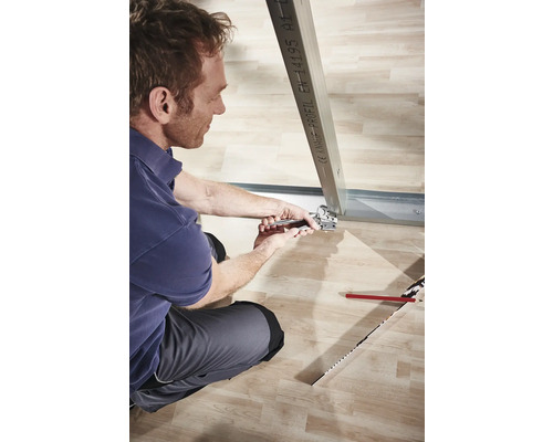 Bărbat fixează profil metalic cu clește în construcție uscată