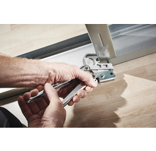 Mâini care folosesc un clește perforator pe un profil metalic