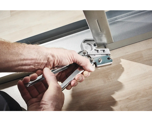 Mâini care folosesc un clește perforator pe un profil metalic