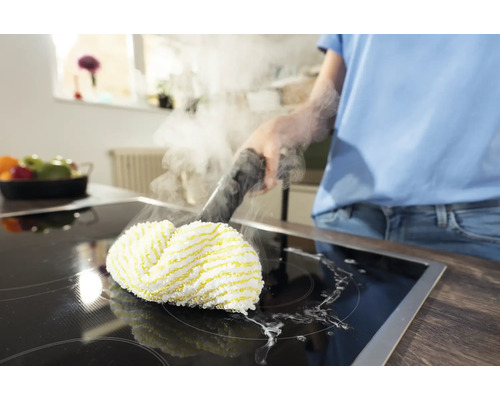 O persoană curăță o plită cu un curățător cu abur.