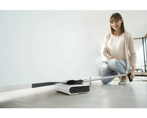 Femeie folosește un măturător electric pentru curățarea podelei