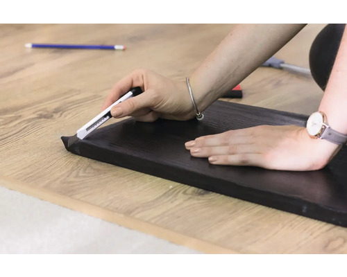 Persoană care taie o plintă cu un cuțit utilitar