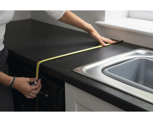 Femeie măsurând un blat de bucătărie cu o ruletă