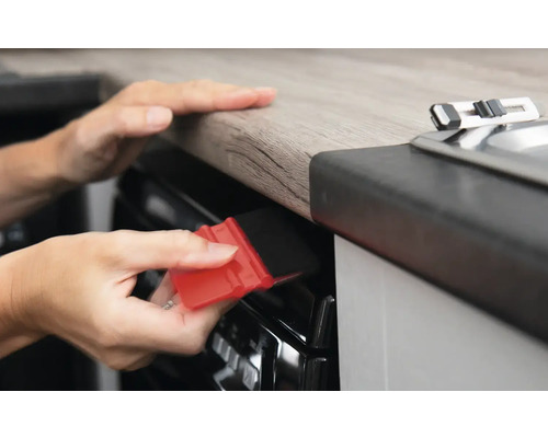 O persoană folosește o racletă pentru aplicarea foliei pe o suprafață într-o bucătărie.