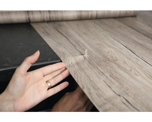 Folie autoadezivă cu aspect de lemn aplicată pe o suprafață.