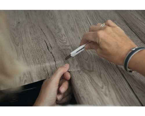 Tăierea unei plăci de podea din vinil cu un cuțit de tăiat.