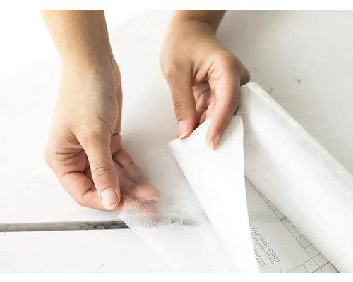 Mâinile îndepărtează folia de protecție de pe folia decorativă autoadezivă